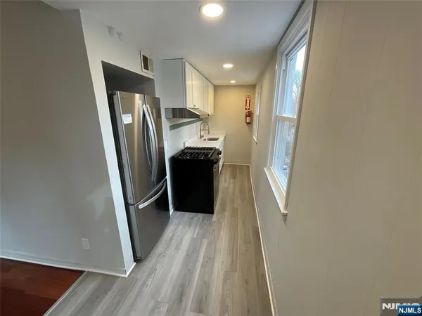 a view of hallway with stainless steel appliances wooden floor and a window