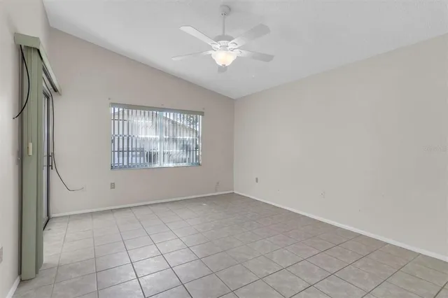 an empty room with windows and ceiling fan