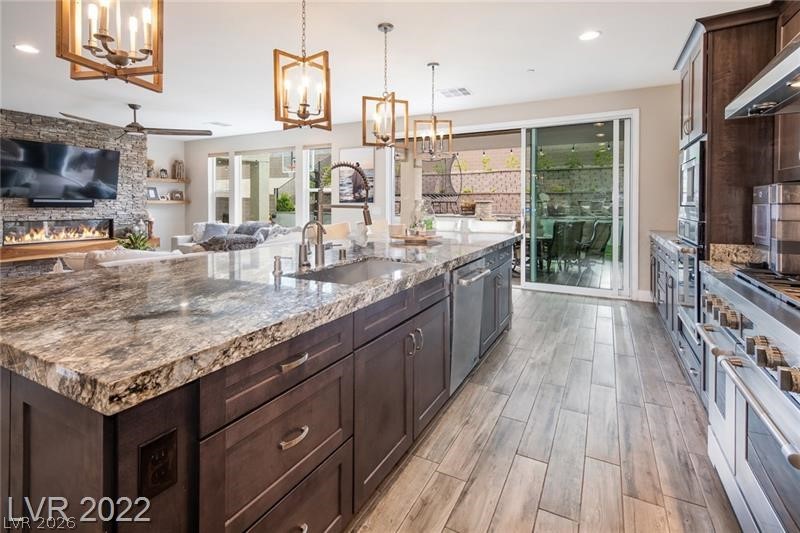 4631 Amazing View Street Las Vegas, NV 89129 - Photo 3 of 33 A spacious, open-concept living area with a stone-accented fireplace and a large kitchen island.