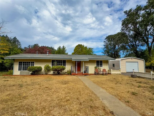 a front view of house with yard and trees in the background