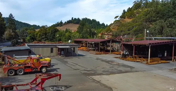 a view of a patio with table and chairs under an umbrella with large trees