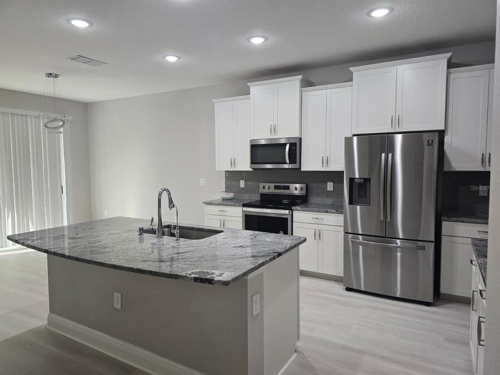 10916 Honor Road Tampa, FL 33625 - Photo 7 of 36 a kitchen with kitchen island granite countertop stainless steel appliances a refrigerator a stove a sink and a refrigerator