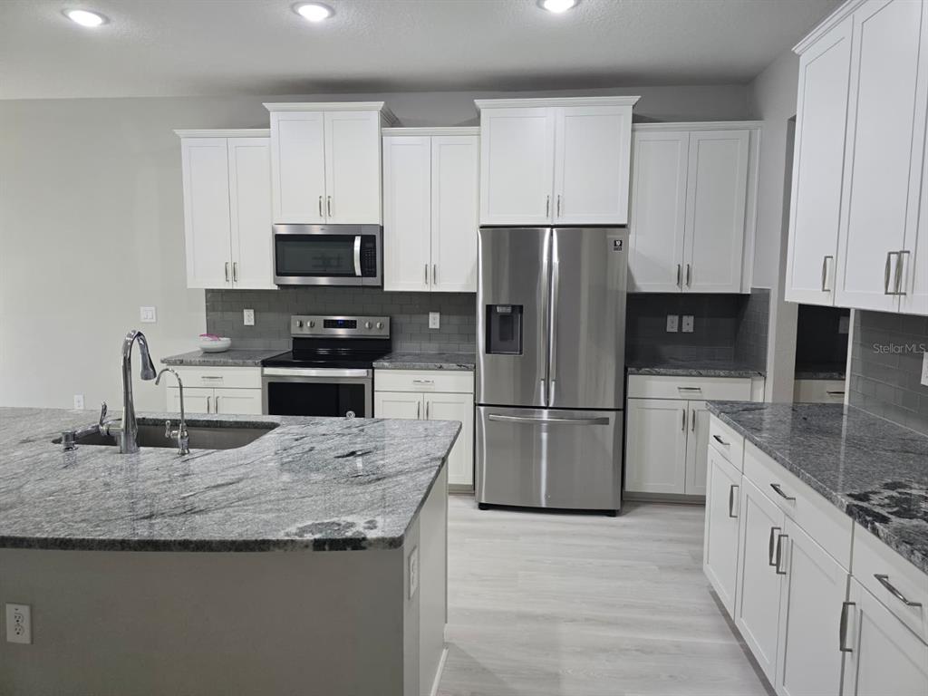 10916 Honor Road Tampa, FL 33625 - Photo 8 of 36 a kitchen with granite countertop a refrigerator a stove a sink a microwave and cabinets