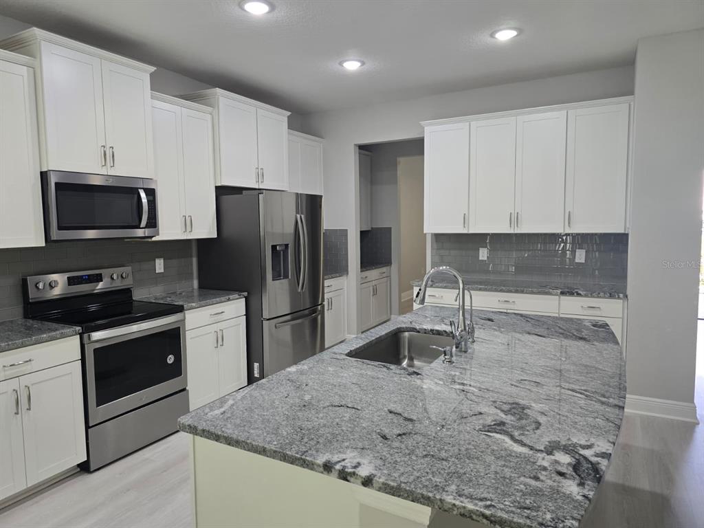 10916 Honor Road Tampa, FL 33625 - Photo 9 of 36 a kitchen with stainless steel appliances granite countertop a stove a refrigerator and a sink