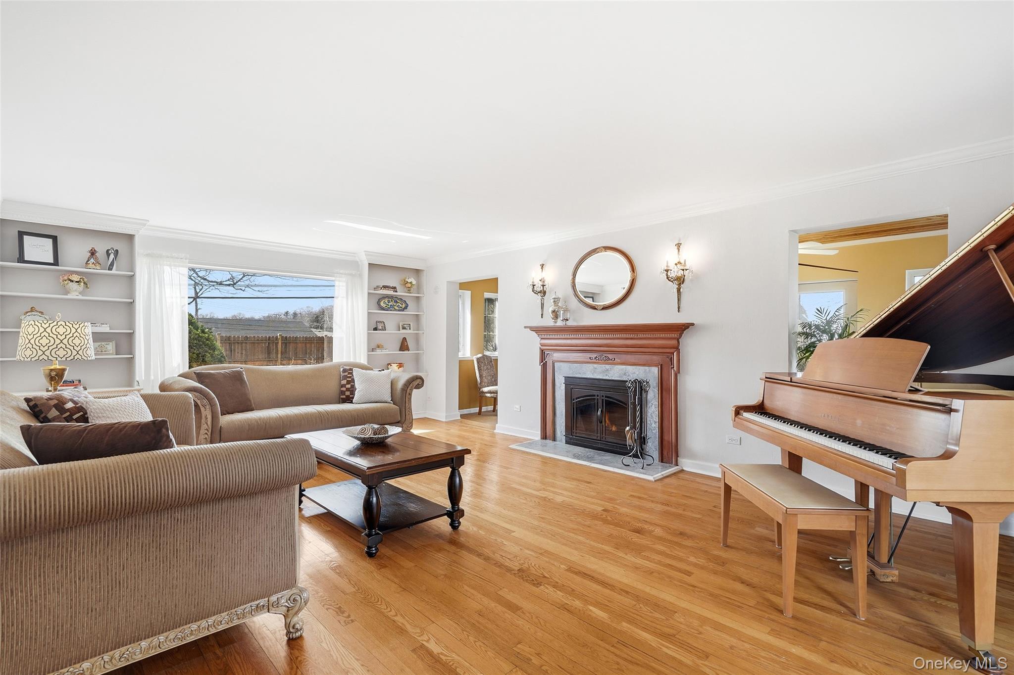 42 Sargent Road Scarsdale, NY 10583 - Photo 4 of 27 A beautifully appointed living room blending warmth and natural light, featuring built-ins, hardwood flooring, a striking fireplace, and refined crown molding.