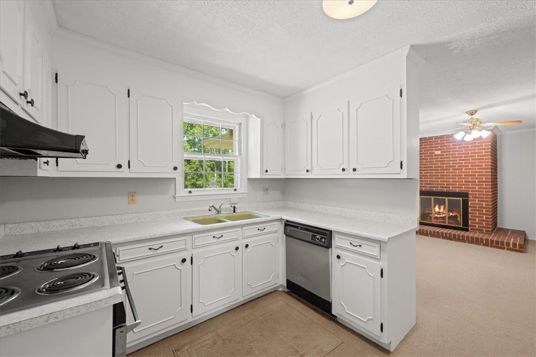 304 Shaw Road Honea Path, SC 29654 - Photo 5 of 39 Bright and functional kitchen featuring essential appliances and an adjoining living space with a fireplace.