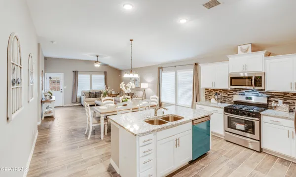 a kitchen with stainless steel appliances kitchen island granite countertop a refrigerator stove and sink