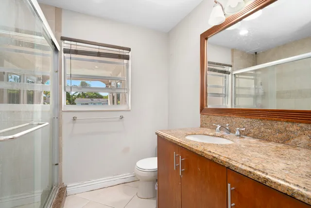 a bathroom with a granite countertop sink toilet and shower