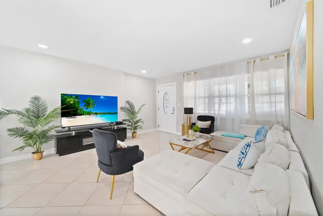 a living room with furniture a flat screen tv and a large window