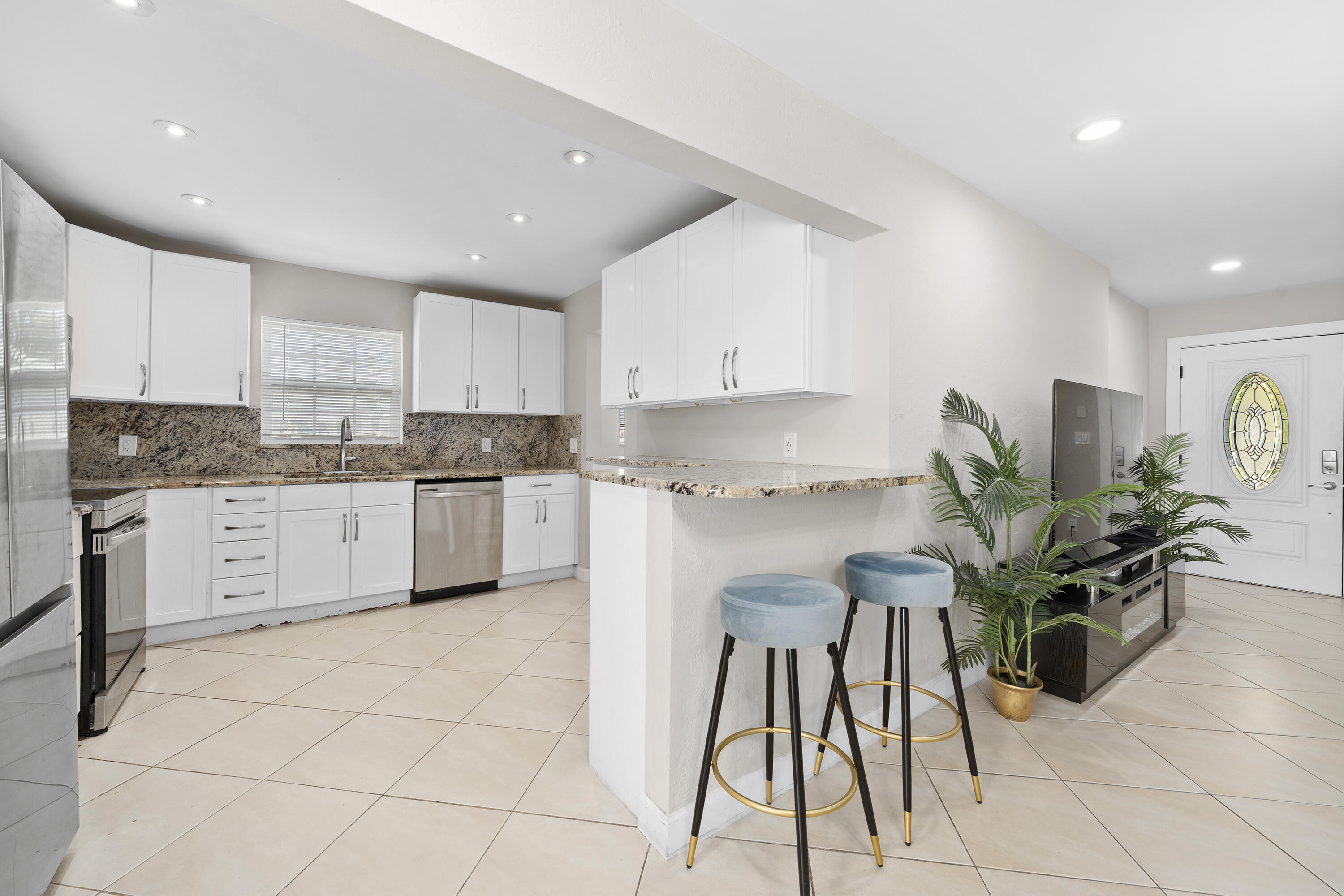 250 Northwest 11th Street Boca Raton, FL 33432 - Photo 7 of 30 a kitchen with stainless steel appliances kitchen island granite countertop a table and chairs in it