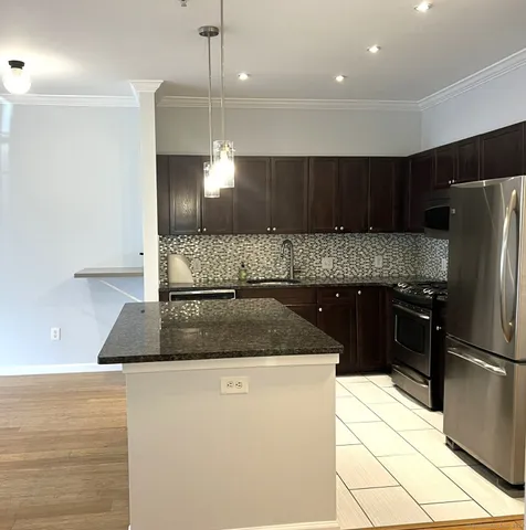 a kitchen with kitchen island granite countertop a refrigerator a stove a sink and a oven