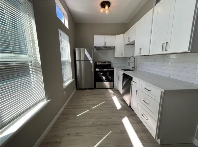 a kitchen with stainless steel appliances granite countertop a refrigerator and white cabinets