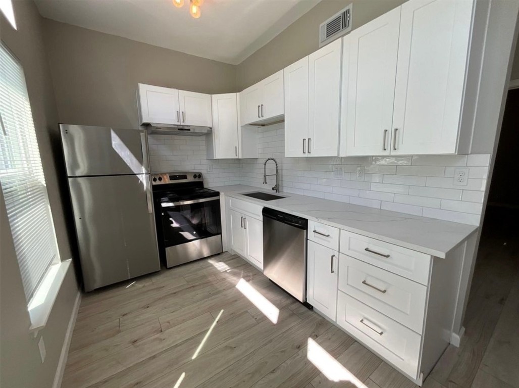 3403 Yupon Street Houston, TX 77006 - Photo 6 of 29 a kitchen with white cabinets and stainless steel appliances