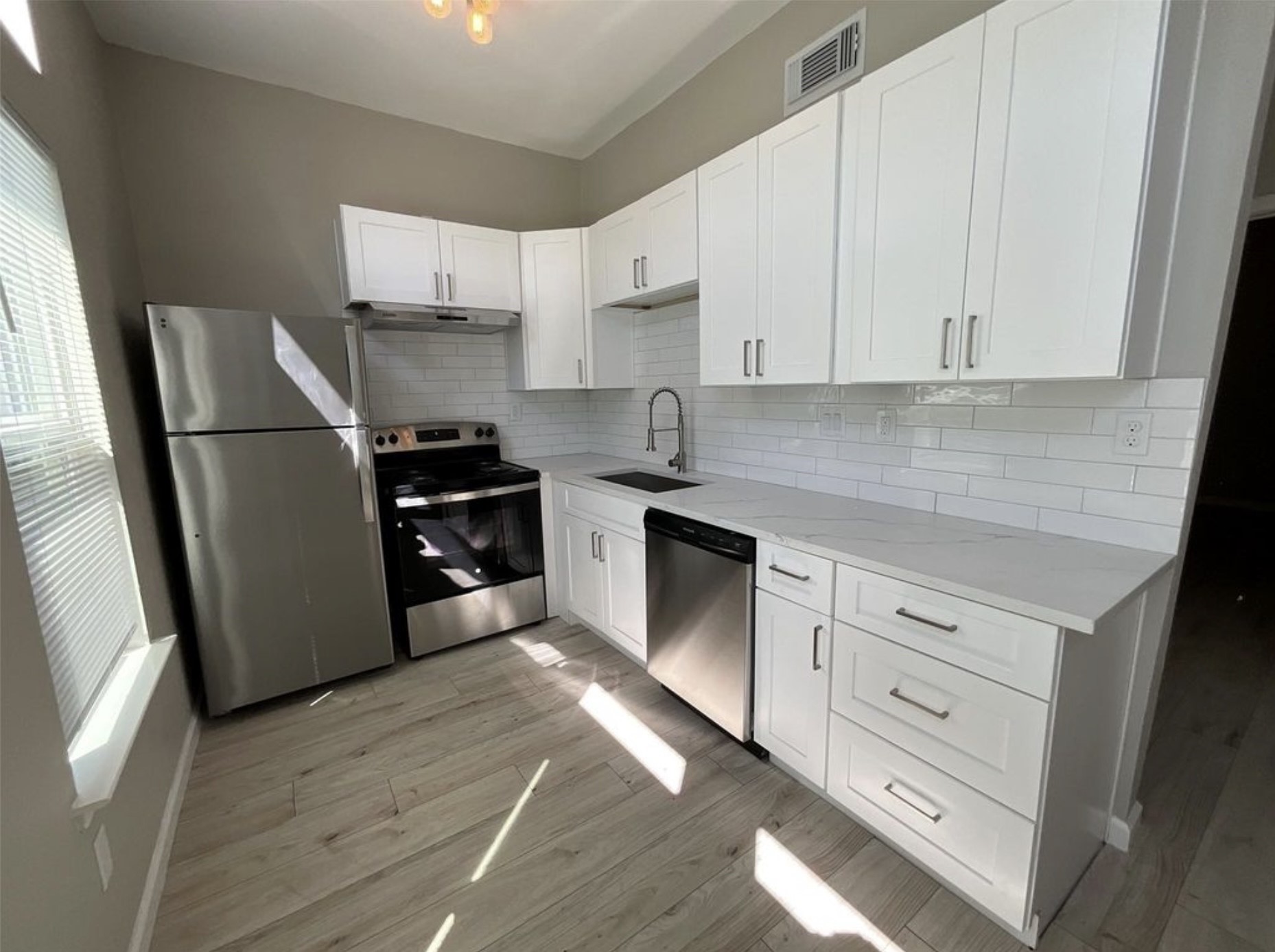 3403 Yupon Street Houston, TX 77006 - Photo 6 of 29 a kitchen with white cabinets and stainless steel appliances