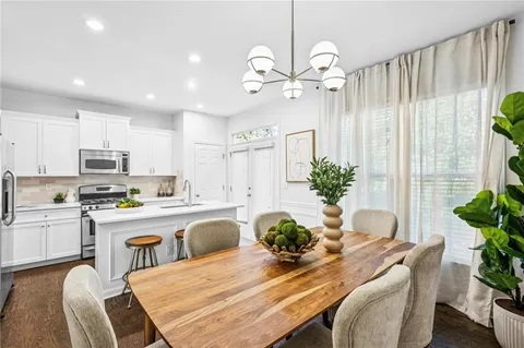 a view of a patio with table and chairs under an umbrella with large trees