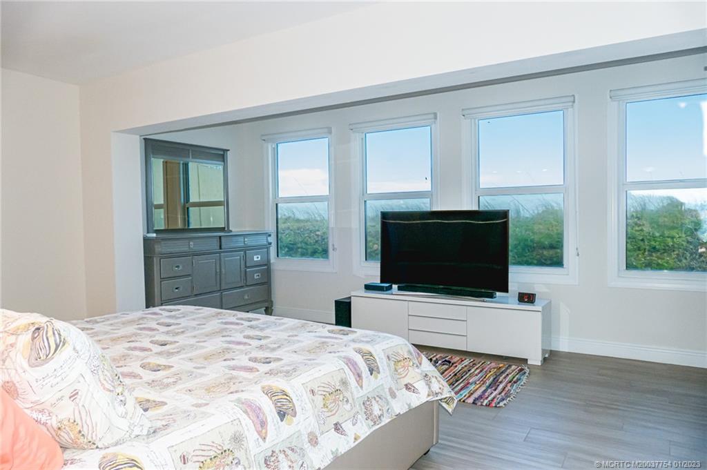 245 Northeast MacArthur Boulevard, Unit 5 Stuart, FL 34996 - Photo 12 of 38 a bedroom with a bed and a flat screen tv
