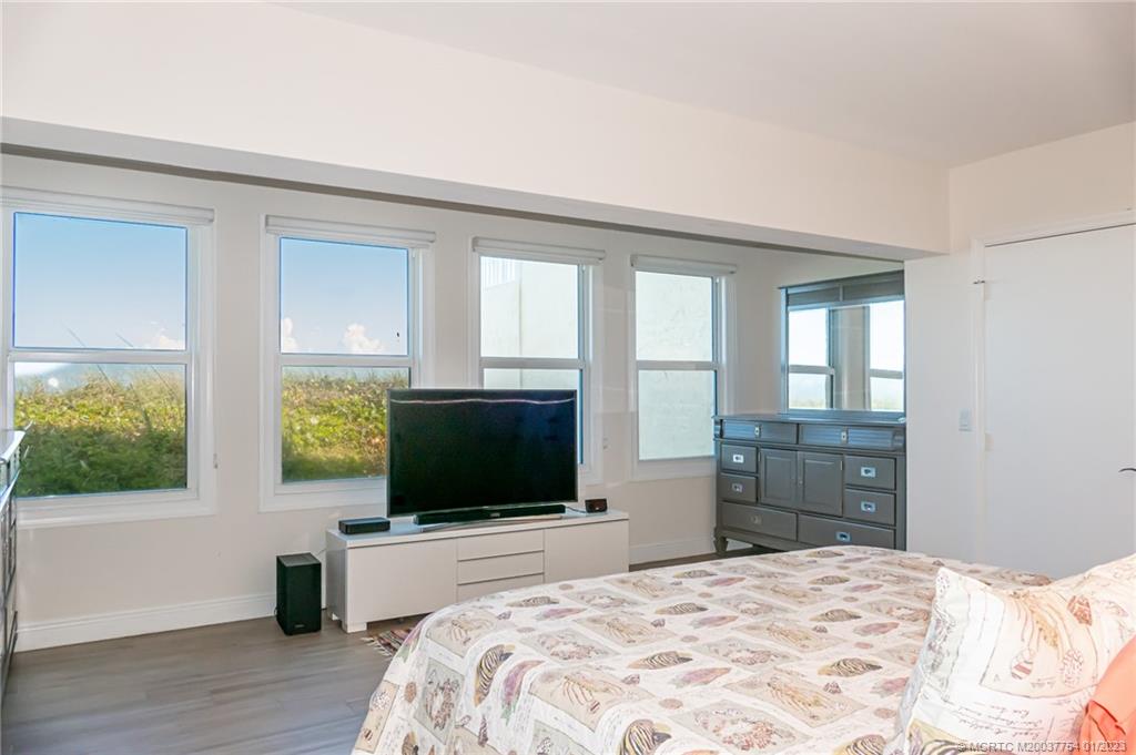 245 Northeast MacArthur Boulevard, Unit 5 Stuart, FL 34996 - Photo 13 of 38 a bedroom with a bed and a flat screen tv