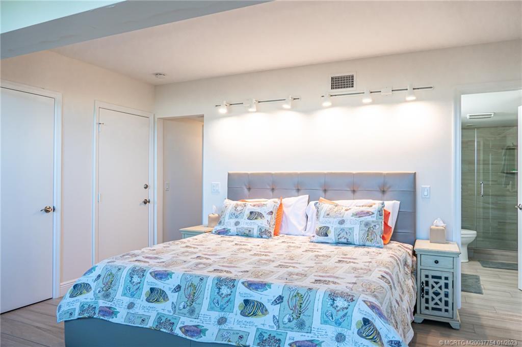 245 Northeast MacArthur Boulevard, Unit 5 Stuart, FL 34996 - Photo 14 of 38 a bedroom with a bed and wooden floor