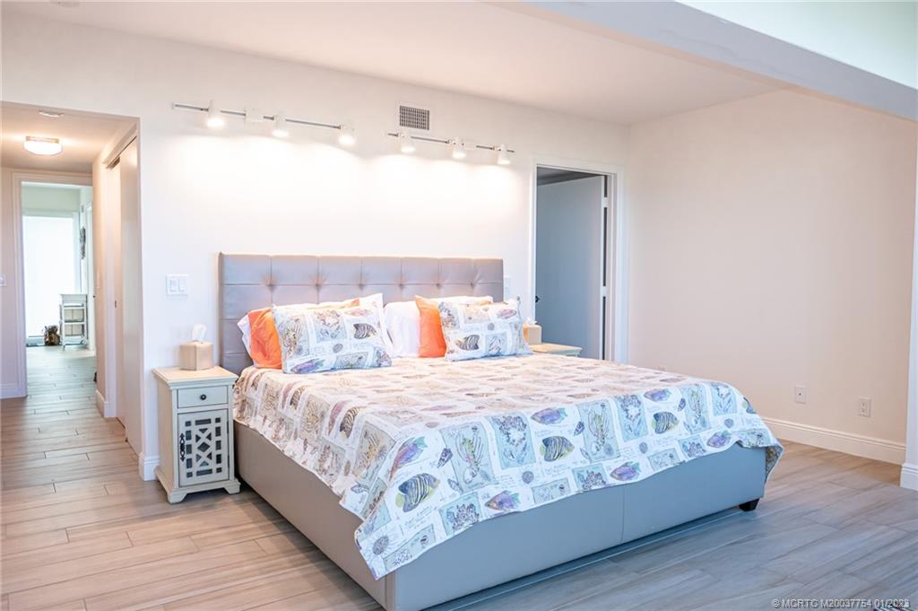 245 Northeast MacArthur Boulevard, Unit 5 Stuart, FL 34996 - Photo 15 of 38 a bedroom with a bed and wooden floor