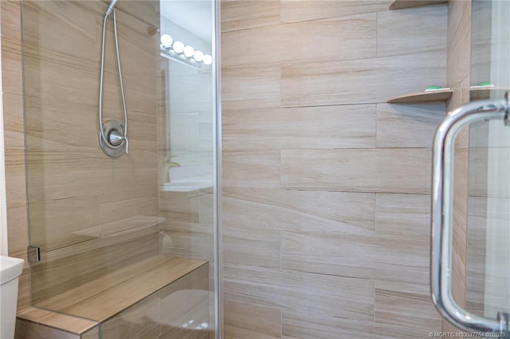 245 Northeast MacArthur Boulevard, Unit 5 Stuart, FL 34996 - Photo 17 of 38 a bathroom with a glass door shower