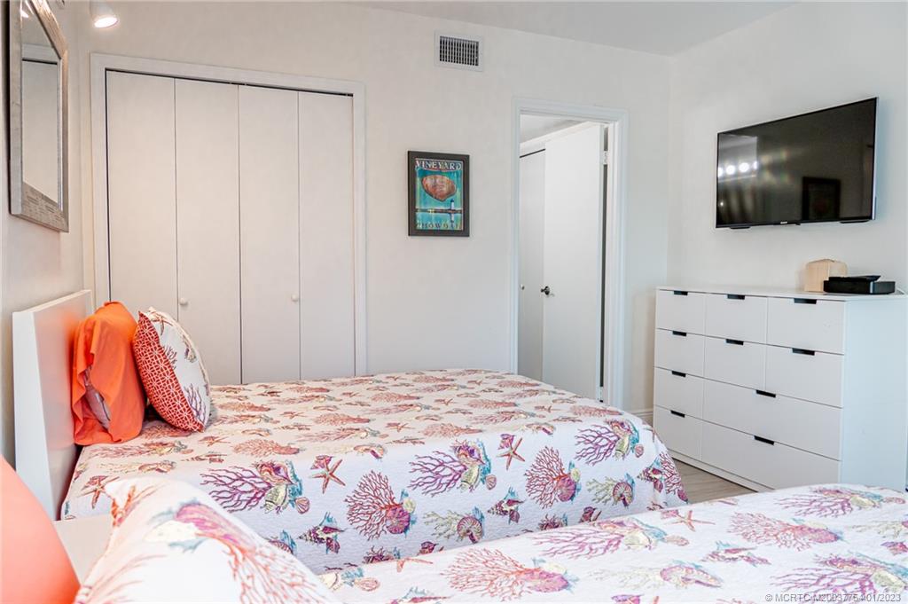 245 Northeast MacArthur Boulevard, Unit 5 Stuart, FL 34996 - Photo 19 of 38 a bedroom with a bed and a flat screen tv in it