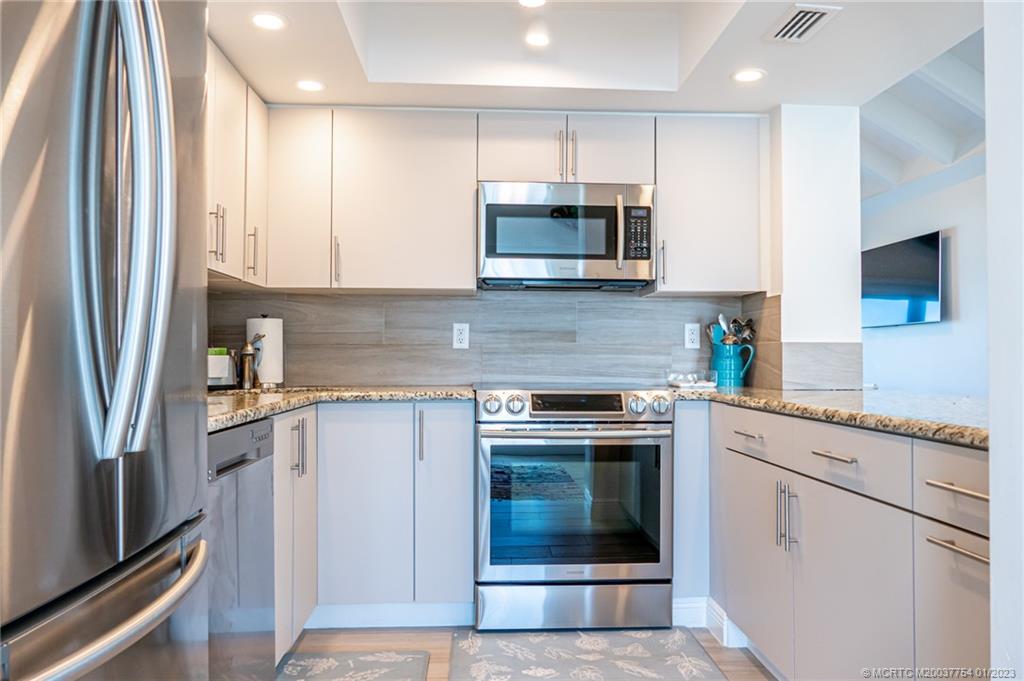 245 Northeast MacArthur Boulevard, Unit 5 Stuart, FL 34996 - Photo 31 of 38 a kitchen with cabinets stainless steel appliances and a counter space