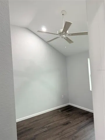 an empty room with wooden floor and fan