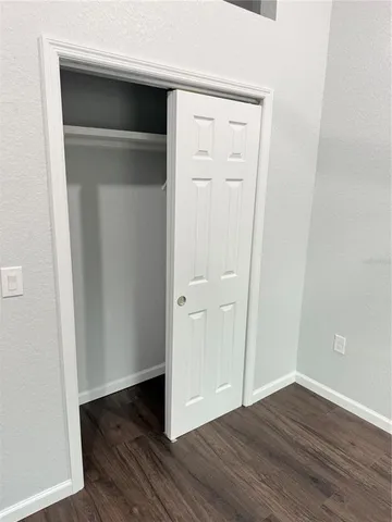 an empty room with wooden floor & closet area