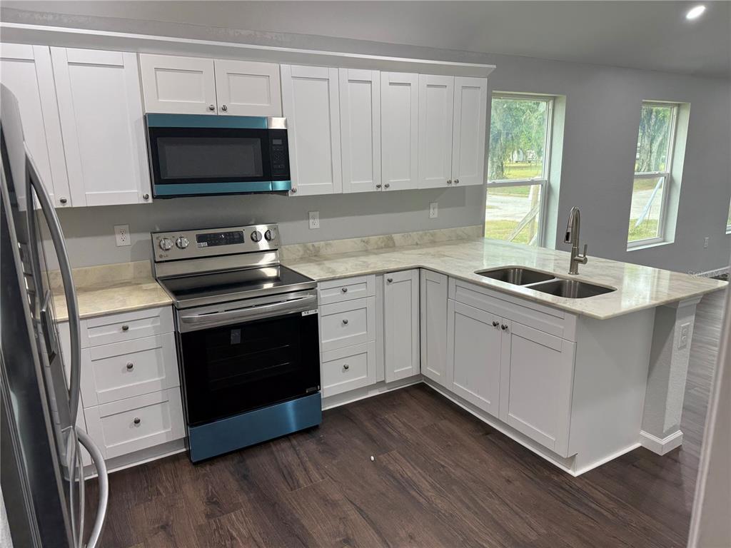 103 South Roger Avenue Arcadia, FL 34266 - Photo 18 of 22 a kitchen with stainless steel appliances kitchen island granite countertop a stove a sink and a microwave