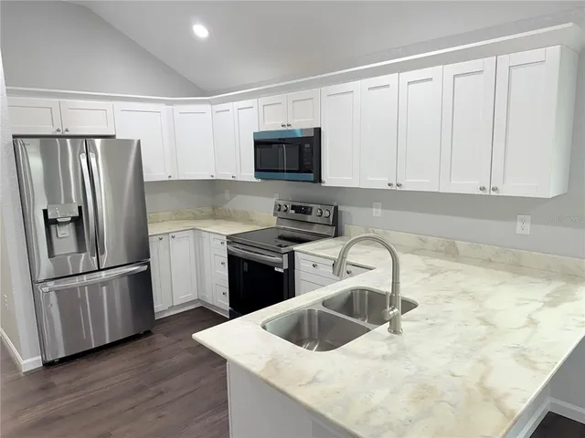 a kitchen with granite countertop a refrigerator sink and microwave