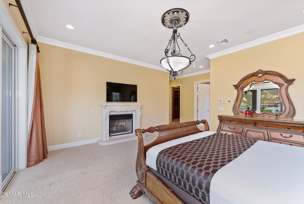 2462 Lost Canyons Drive Simi Valley, CA 93065 - Photo 35 of 50 a bedroom with a bed chandelier and fireplace