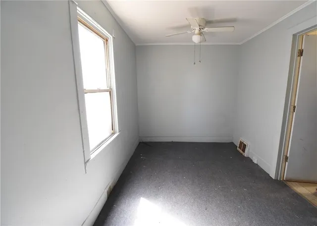 an empty room with a window and a fan