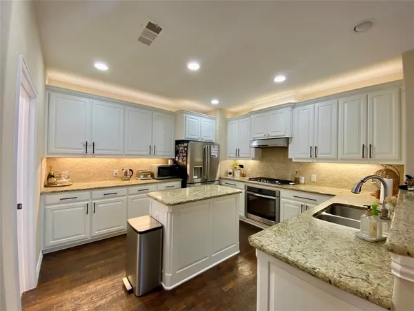 a kitchen with granite countertop a sink stove and refrigerator