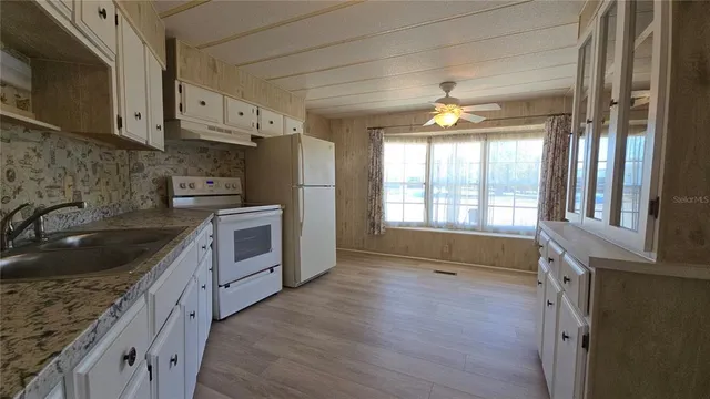 a kitchen with granite countertop a stove a sink and a refrigerator