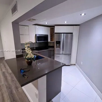 a kitchen with stainless steel appliances a sink a stove a microwave a refrigerator and cabinets