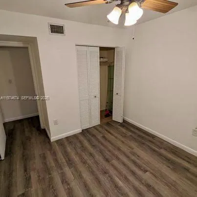 a view of an empty room with wooden floor and a chandelier