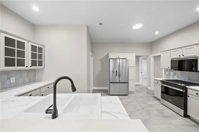 a kitchen with stainless steel appliances kitchen island a refrigerator sink and cabinets