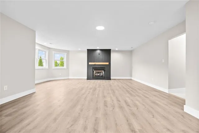 a view of an empty room with a window and a kitchen
