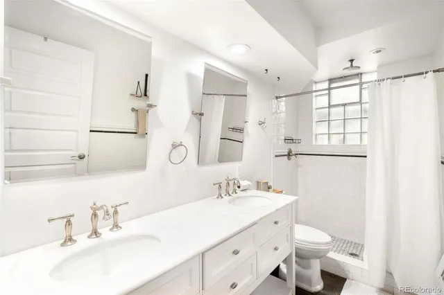 a bathroom with a double vanity sink toilet and mirror