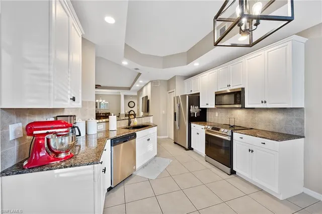 a kitchen with stainless steel appliances granite countertop a sink and dishwasher a stove top oven with white cabinets