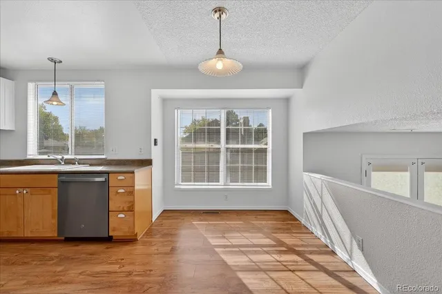 a view of an empty room with a kitchen and a window