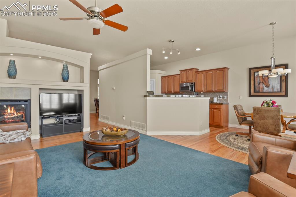617 Concerto Drive Colorado Springs, CO 80906 - Photo 11 of 46 This inviting open plan living area features a fireplace with a tiled surround, nooks for tv and artwork displays, a ceiling fan, and hardwood flooring that extends into the adjacent dining area and kitchen