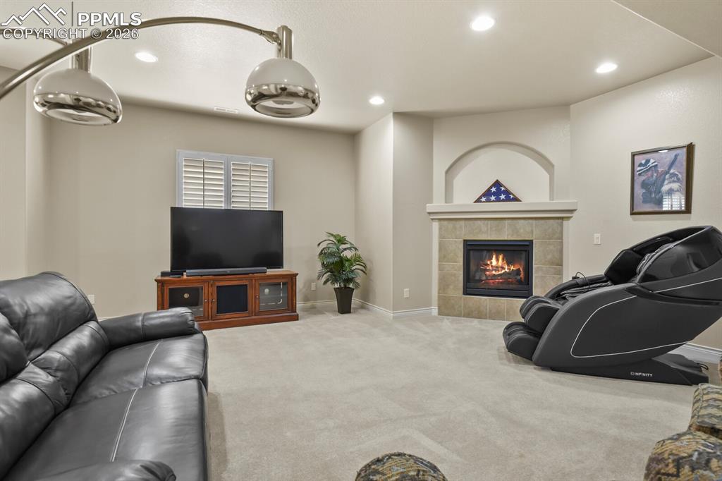 617 Concerto Drive Colorado Springs, CO 80906 - Photo 30 of 46 This inviting living space features light-colored carpeting, recessed lighting, and a corner gas fireplace with a tiled surround