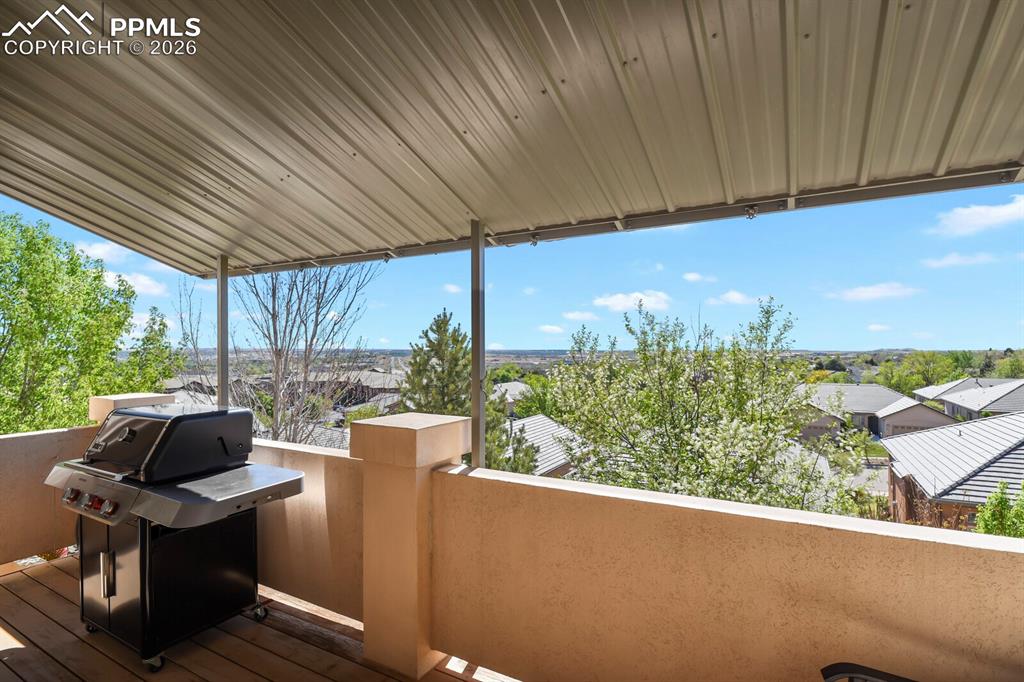 617 Concerto Drive Colorado Springs, CO 80906 - Photo 38 of 46 Outdoor living area featuring a covered patio, a stone half-wall, and scenic views of the surrounding neighborhood and city. Lots of trees.