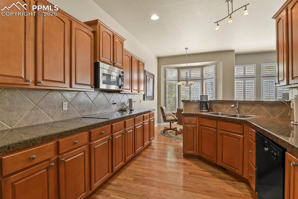 617 Concerto Drive Colorado Springs, CO 80906 - Photo 8 of 46 Well-appointed kitchen featuring hardwood floors, warm-toned cabinetry, a tiled backsplash.