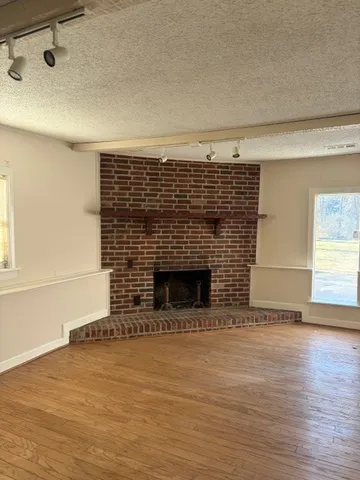 a view of empty room with wooden floor and fireplace