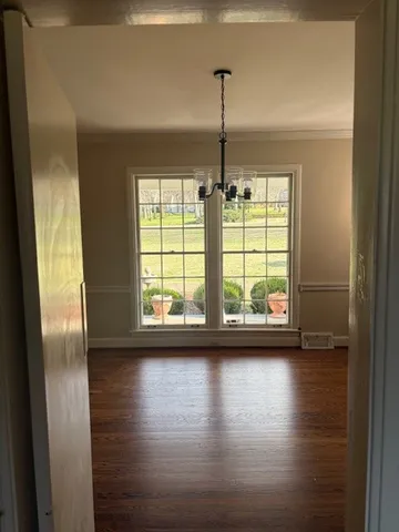 a view of empty room with wooden floor and window