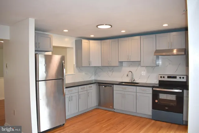 a kitchen with a sink a refrigerator and white cabinets