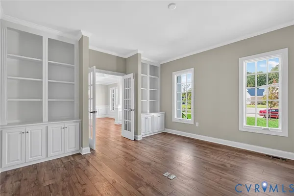 a view of an empty room with window and wooden floor