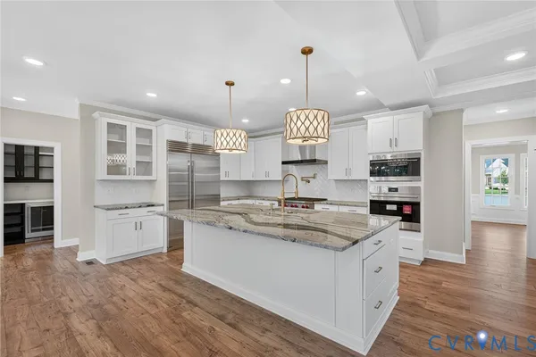 a large kitchen with stainless steel appliances granite countertop a sink a stove and a wooden floors
